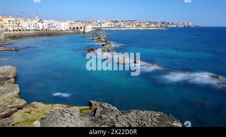 La costa rocciosa orientale dell'isola di Ortigia, Siracusa, Sicilia, Italia, con acque limpide e colorate Foto Stock