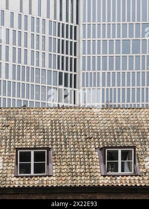 Gli stili architettonici contrastanti di Malmö, Svezia, sono catturati qui, mostrando il tetto in tegole vecchio stile di un edificio storico nel Foto Stock
