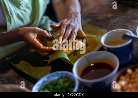 Primo piano di mani che preparano l'hallaca o il tamale. Concetto di cucina tradizionale Foto Stock