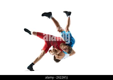 Due lottatori greco-romani in uniforme rossa e blu, isolati su sfondo bianco. Giovani uomini competitivi Foto Stock