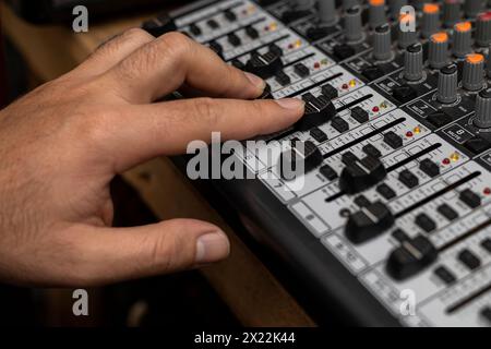 Primo piano di una mano maschio che cambia volume sulla piastra di miscelazione. Creazione di musica, concetto dj Foto Stock