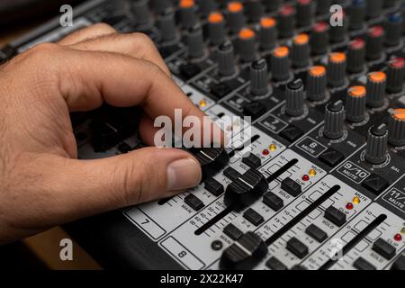 Primo piano di una mano maschio che cambia volume sulla piastra di miscelazione. Creazione di musica, concetto dj Foto Stock