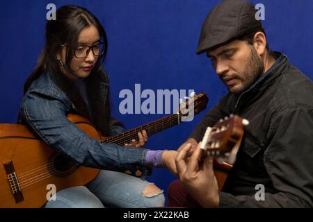 Il giovane insegnante latino-americano insegna chitarra. Lezioni di musica concettuale Foto Stock