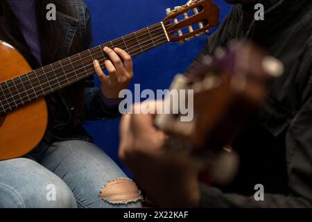 Un insegnante latinoamericano irriconoscibile corregge e insegna gli accordi con la chitarra. Lezioni di musica concettuale Foto Stock