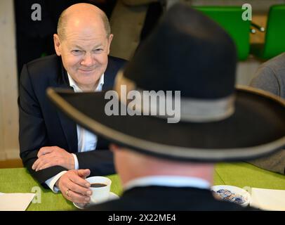 Dresda, Germania. 19 aprile 2024. Il Cancelliere federale Olaf Scholz (SPD) parla con il maestro falegname Ralf Lepski durante la sua visita ad una società di costruzioni in legno con sede a Dresda. Insieme al presidente della Confederazione tedesca dell'artigianato qualificato (ZDH) e al presidente della camera dell'artigianato qualificato di Dresda, Scholz partecipa ad un tour dei laboratori dell'artigianato specializzato e poi parla con i dipendenti dell'azienda delle problematiche attuali nel settore dell'artigianato specializzato. Crediti: Robert Michael/dpa/Alamy Live News Foto Stock