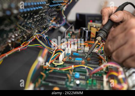 Mani di un tecnico elettronico latino-americano che ripara il circuito di un pianoforte con saldatore e stagno nel centro di assistenza. Riparazione concettuale, Musi Foto Stock