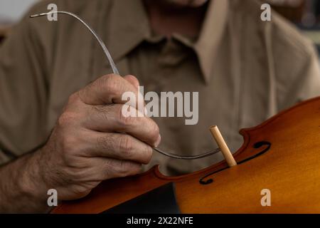 Liutaio latinoamericano che colloca un palo sonoro tra la parte superiore e la parte inferiore del violino. Strumenti a corda Foto Stock