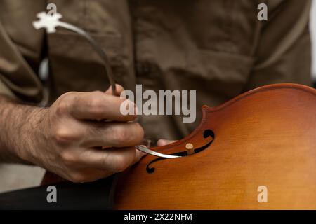 Liutaio latinoamericano che colloca un palo sonoro tra la parte superiore e la parte inferiore del violino. Strumenti a corda Foto Stock