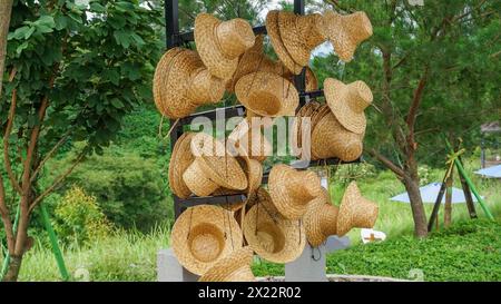 Cappelli da cesto appesi, cappelli realizzati con materiali naturali, foglie di canna. cappello estivo in fibra naturale di paglia. Foto Stock