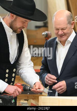 Dresda, Germania. 19 aprile 2024. Il Cancelliere federale Olaf Scholz (SPD, r) ha il maestro falegname Felix Lepski che spiega come avvitare una vite durante la sua visita a una società di costruzioni in legno di Dresda. Scholz si unisce al presidente della Confederazione tedesca dell'artigianato qualificato (ZDH) e al presidente della camera di Dresda dell'artigianato qualificato in un tour dei laboratori dell'azienda e parla ai dipendenti delle questioni attuali nel settore dell'artigianato specializzato. Crediti: Robert Michael/dpa/Alamy Live News Foto Stock