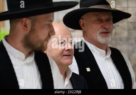 Dresda, Germania. 19 aprile 2024. Il Cancelliere Olaf Scholz (SPD, centro) è guidato attraverso la sala di produzione dai maestri carpentieri Felix Lepski (a sinistra) e Ralf Lepski (a destra) durante la sua visita a una società di costruzioni in legno di Dresda. Scholz si unisce al presidente della Confederazione tedesca dell'artigianato qualificato (ZDH) e al presidente della camera di Dresda dell'artigianato qualificato in un tour dei laboratori e parla con i dipendenti dell'azienda delle questioni attuali nel settore dell'artigianato specializzato. Crediti: Robert Michael/dpa/Alamy Live News Foto Stock