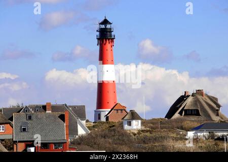 Faro, Hoernum, Sylt, North Frisian Island, Schleswig Holstein, dietro una fila di case si trova un faro a strisce rosse e bianche, Sylt Foto Stock