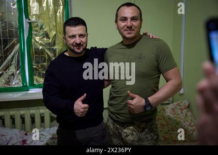 Slovyansk, Ucraina. 19 aprile 2024. Il presidente ucraino Volodymyr Zelenskyy, a sinistra, posa per un selfie con un soldato ferito della 95a brigata d'assalto aerea separata durante una visita a un ospedale militare nella regione del Donbas, 19 aprile 2023 a Slovyansk, Oblast di Donetsk, Ucraina. Credito: Handout/Ufficio stampa presidenziale ucraino/Alamy Live News Foto Stock