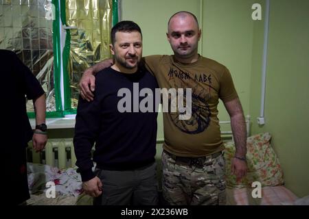 Slovyansk, Ucraina. 19 aprile 2024. Il presidente ucraino Volodymyr Zelenskyy, a sinistra, posa per un selfie con un soldato ferito della 95a brigata d'assalto aerea separata durante una visita a un ospedale militare nella regione del Donbas, 19 aprile 2023 a Slovyansk, Oblast di Donetsk, Ucraina. Credito: Handout/Ufficio stampa presidenziale ucraino/Alamy Live News Foto Stock