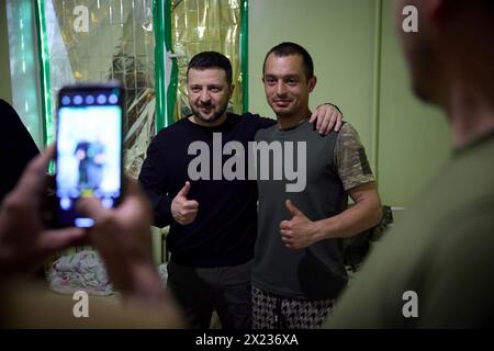 Slovyansk, Ucraina. 19 aprile 2024. Il presidente ucraino Volodymyr Zelenskyy, a sinistra, posa per un selfie con un soldato ferito della 95a brigata d'assalto aerea separata durante una visita a un ospedale militare nella regione del Donbas, 19 aprile 2023 a Slovyansk, Oblast di Donetsk, Ucraina. Credito: Handout/Ufficio stampa presidenziale ucraino/Alamy Live News Foto Stock