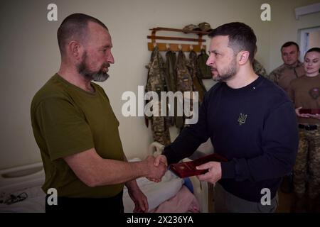 Slovyansk, Ucraina. 19 aprile 2024. Il presidente ucraino Volodymyr Zelenskyy, giusto, assegna una medaglia di stato a un soldato ferito della 95a brigata d'assalto aereo separata durante una visita ad un ospedale militare nella regione del Donbas, 19 aprile 2023 a Slovyansk, Oblast di Donetsk, Ucraina. Credito: Handout/Ufficio stampa presidenziale ucraino/Alamy Live News Foto Stock