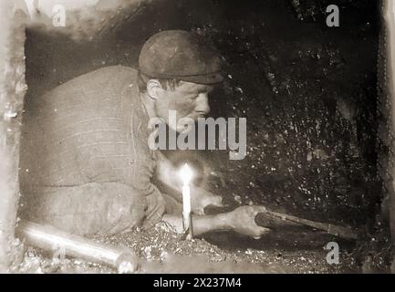 Estrazione del carbone in Gran Bretagna. Una vecchia fotografia che mostra un minatore gallese che lavora a lume di candela sulla faccia del carbone. Foto Stock