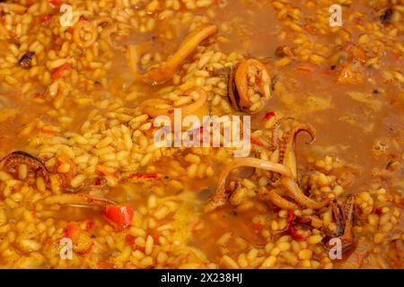 Immergetevi nell'arte della cucina spagnola mentre i colori vivaci e gli allettanti aromi della paella prendono vita durante la sua preparazione Foto Stock