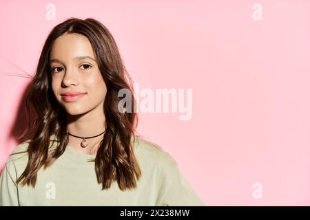 Un'adolescente elegante e vivace posa con sicurezza davanti a uno sfondo rosa. Foto Stock