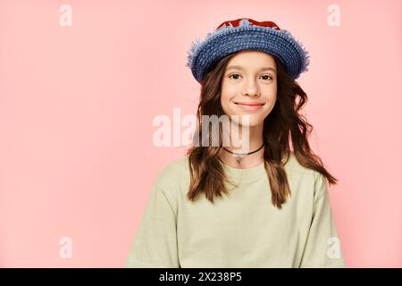 Un'adolescente elegante posa energica con un cappello blu e una camicia verde. Foto Stock