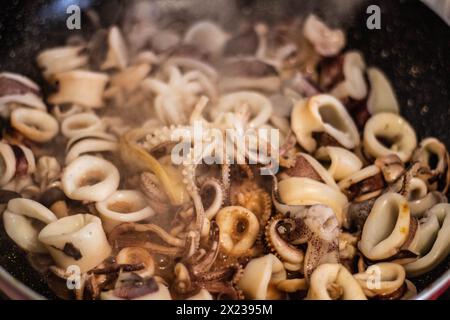 Concediti il brivido e l'aroma della frittura di calamari appena cucinata nella padella. Provate l'arte culinaria e la delizia della cucina mediterranea Foto Stock