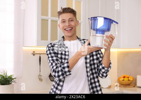 Uomo felice con la caraffa del filtro dell'acqua in cucina Foto Stock