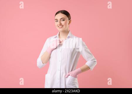 Cosmetologo in uniforme medica su sfondo rosa Foto Stock