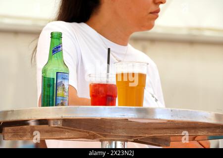 Due bicchieri di plastica con birra, una lunga bevanda e una bottiglia di birra vuota sono posti su un tavolo. Foto Stock