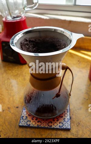 Versare il bicchiere sulla macchina per il caffè su piastrelle in ceramica. Shot verticale, completo, nessuno, versare sulla macchina per il caffè con caffè appena estratto Foto Stock