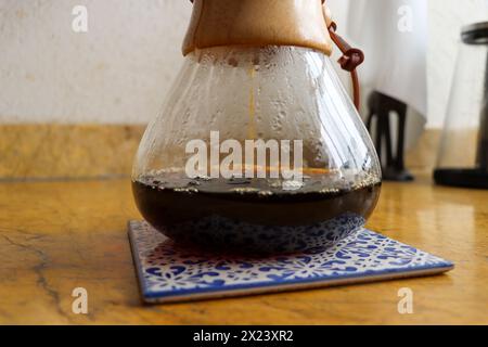 Versare il bicchiere sulla macchina per il caffè su piastrelle in ceramica. Shot verticale, completo, nessuno, versare sulla macchina per il caffè con caffè appena estratto Foto Stock