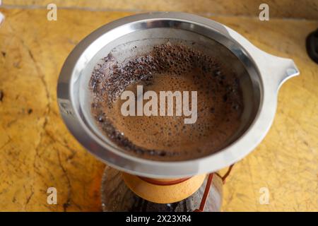 Versare il bicchiere sulla macchina per il caffè su piastrelle in ceramica. Shot verticale, completo, nessuno, versare sulla macchina per il caffè con caffè appena estratto Foto Stock