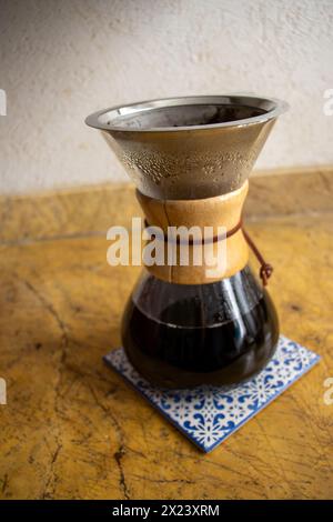 Versare il bicchiere sulla macchina per il caffè su piastrelle in ceramica. Shot verticale, completo, nessuno, versare sulla macchina per il caffè con caffè appena estratto Foto Stock