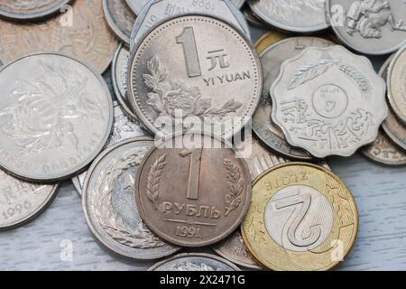 foto di una varietà di monete metalliche su uno sfondo chiaro. Monete del rublo russo, yuan cinese e altre monete varie da vicino, vista dall'alto. Foto Stock