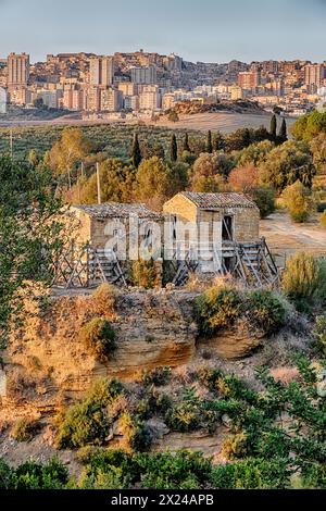 Due rustici edifici agricoli si trovano dall'altra parte del burrone della Valle dei Templi vicino alla città di Agrigento in Sicilia. Foto Stock