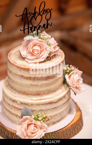 Una torta nuziale in spugna a due livelli con decorazioni floreali Foto Stock