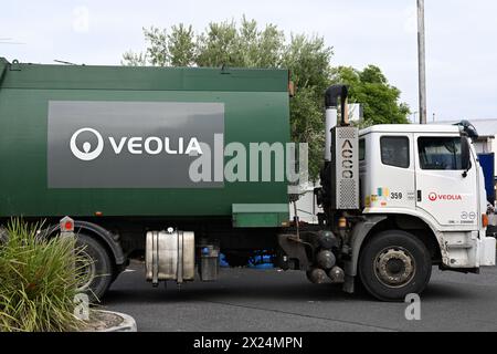 Vista laterale di un camion della spazzatura verde e bianca Veolia in un piccolo parcheggio, durante una giornata coperto Foto Stock