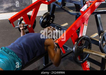 Un giovane atleta afroamericano in palestra che solleva pesi su panca Foto Stock