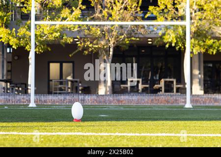 Una palla da rugby appoggiata sul tee, pronta per un calcio d'inizio in campo all'aperto, spazio copia Foto Stock