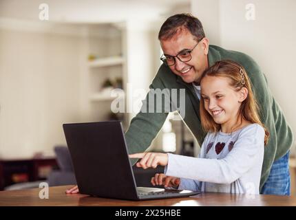 Padre, ragazza e laptop per l'apprendimento remoto a casa, Internet e sito Web scolastico o i compiti online. Papà, figlia e aiuto con la lezione a tavola Foto Stock