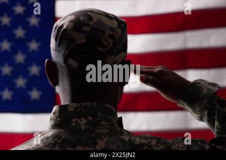 Soldato americano che saluta con la bandiera americana nel campo militare Foto Stock