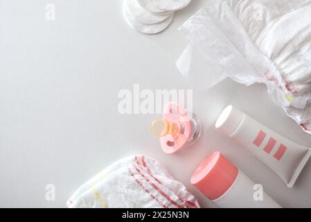 Accessori rosa per cambiare il pannolino e prendersi cura della pelle del bambino con crema e talco in polvere. Vista dall'alto. Foto Stock