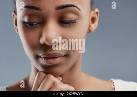 Primo piano intimo di una giovane donna premurosa, la sua espressione serena su uno sfondo dalle tonalità fresche Foto Stock