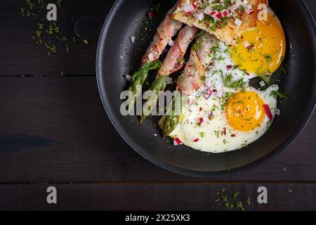 Colazione Keto. Uova fritte con asparagi in pancetta e pane tostato. Vista dall'alto, disposizione piatta Foto Stock