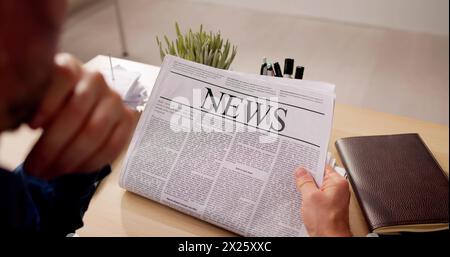 Uomo d'affari che legge il giornale alla scrivania al lavoro Foto Stock