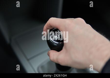 Uomo che tiene in mano la leva del selettore marce del cambio manuale mantiene il cambio nell'abitacolo della vettura Foto Stock