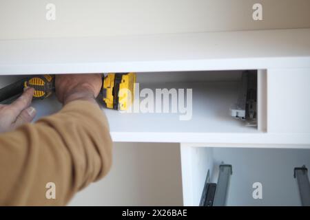 L'uomo installazione di scaffalature in legno su staffe per installazione a parete di un ripiano Foto Stock