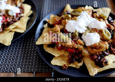 Piatto appetitoso su un piatto: Nachos di patatine di mais con carne macinata fritta e guacamole, fagioli, salsa, jalapenos vista dall'alto. Cucina messicana fatta in casa Foto Stock