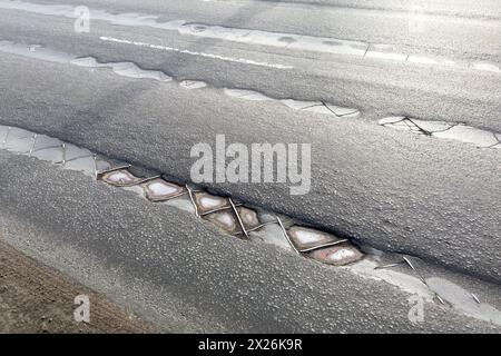 Affondamento su strada asfaltata di scarsa qualità su un ponte in città, asfalto di bassa qualità, necessità di riparazione. Foto Stock