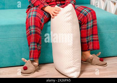 Piedi in pigiama e ciabatte. Giovane donna in pantofole a casa. gambe delle donne con pigiama appeso al letto Foto Stock