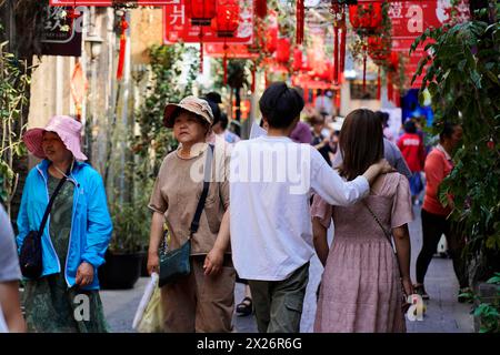 Passeggiando attraverso il quartiere restaurato di Tianzifang, la gente passeggia attraverso una strada dello shopping con striscioni rossi e un tocco urbano, Shanghai, Cina Foto Stock